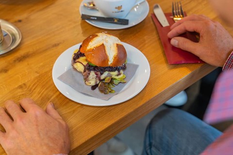 A burger on a pretzel bun is served on a table in the restaurant, autumn creations, Cafe Kuh,