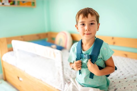Portrait of a schoolboy with school bag ready for first day at school smiling at camera in the