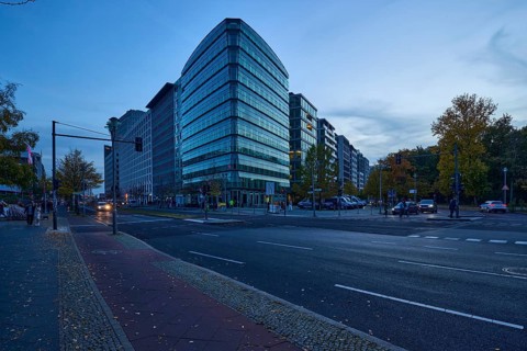 Junction of Lennéstraße with Ebertstraße and glass facade of a commercial building at blue hour in