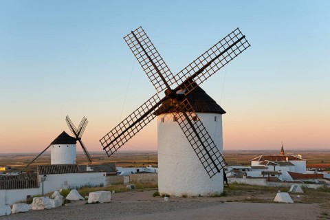 White windmills stand in a rural landscape under a gentle morning sky, Campo de Criptana, Ciudad