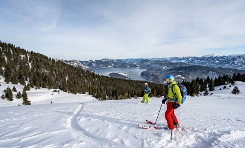 Two skiers skiing down the Simetsberg, view of Walchensee and mountain panorama, Estergebirge,