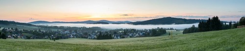 Panorama of the village view with the church of St. Mary's Assumption in the morning fog in front