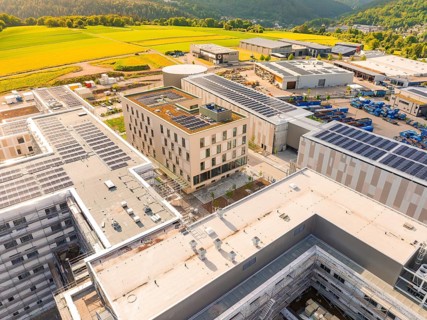 Building with solar panels on the roof, surrounded by fields and industrial plants, construction of