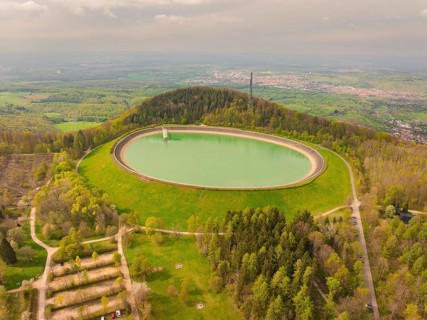 Upper reservoir hill with reservoir and forest, observation tower in the background under cloudy