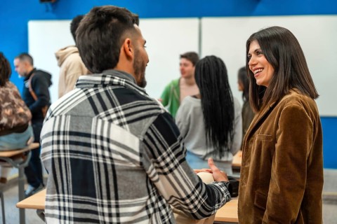 Multi ethnic university students chatting with their teacher after class, discussing lesson topics