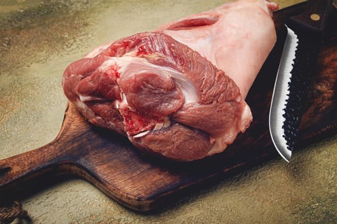 Raw pork knuckle, on a wooden chopping board, close-up, top view, no people