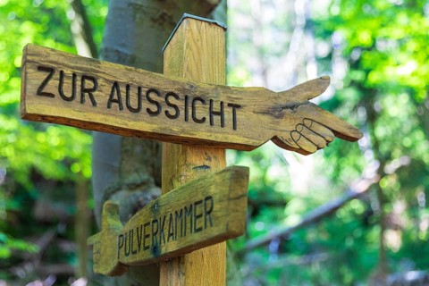 Wooden hiking sign points the way to the view or to the powder magazine, at the Zschirnstein,