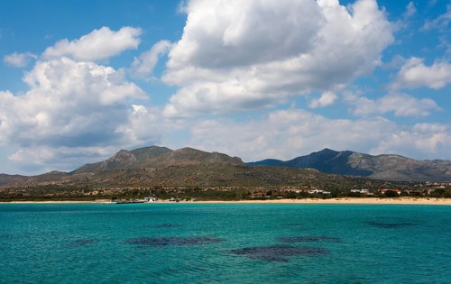 A wide view over the sea with mountains and clouds in the background, view to Pounta beach near