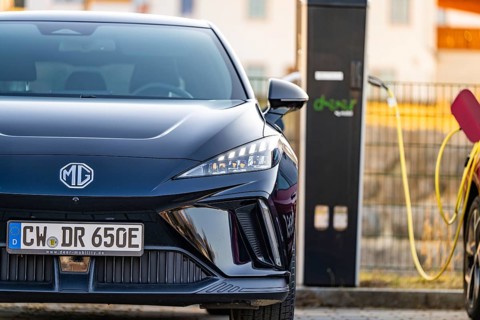 Front of a black electric car with licence plate next to a charging station, Deer E- Carsharing