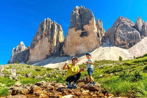 Mother and child waving near tre cime di lavaredo, dolomites, italy, enjoying summer vacation