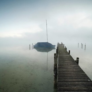 Quiet autumn morning on Lake Chiemsee, jetty with sailing boat in dense fog, Prien am Chiemsee,