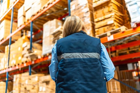 Low angle view of the rear view of a caucasian blonde woman working in a distribution warehouse