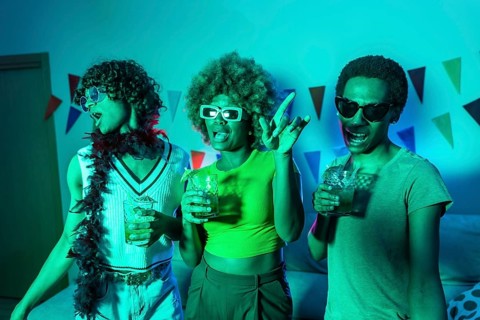 Multi-ethnic young students dancing and drinking alcohol during night party at home