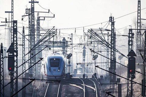 Deutsche Bahn AG tracks with ICE train against the light. Overhead line, signals and infrastructure