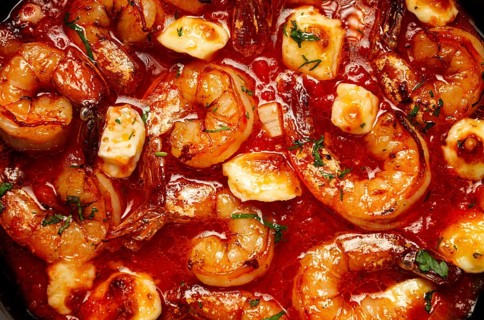 Greek saganaki, in an iron pan, saganaki with shrimp, shrimp in tomato sauce, with pepper and feta