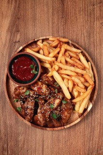 Barbecue chicken wings, sprinkled with sesame seeds, with French fries, and sauce, on a wooden