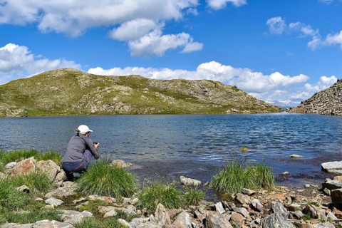 Woman photographing high alpine mountain lake at the Weiße Spitze, in the background the