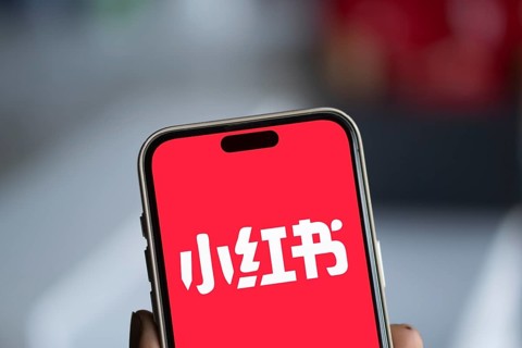 RedNote (Xiaohongshu) logo is displayed on iPhone