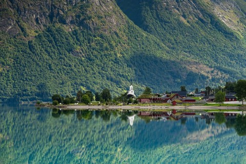 Reflection in lake Oppstrynsvatnet, white stave church, Oppstryn, Stryn, Norwege