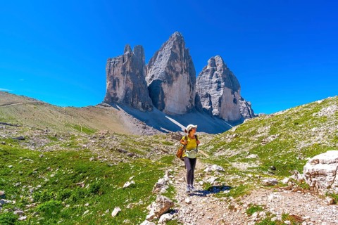 Female tourist walking on the trail leading to the tre cime di lavaredo, enjoying the breathtaking