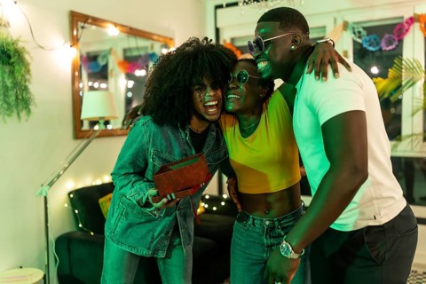 African young woman hugs her friends gratefully for a birthday gift at home