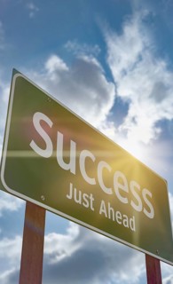 Success just ahead green road sign against a blue sky and clouds