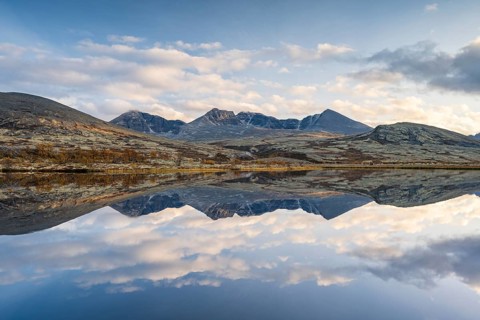 Reflection of the autumn landscape in Rondane National Park, mountains Høgronden, Midtronden and