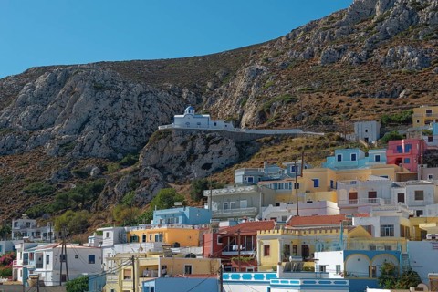 Colourful houses of Menetes with the chapel of Agios Spiridonas on a rock in front of a hill,