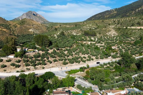 Green hills and a village on a winding road, surrounded by lush natural scenery, near Bedmar y