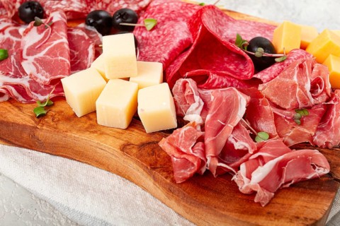 Assorted, sliced meat appetizer, prosciutto, salami and ham, with cheese and olives, on a wooden