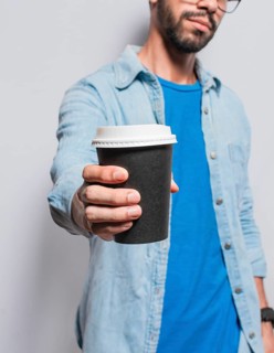 Close up of person offering a coffee to go, Young man offering the camera a coffee to go, Handsome