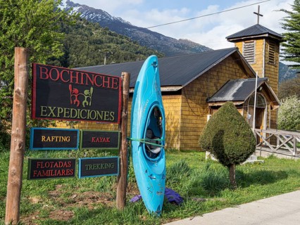 Signpost of tour operator for rafting, kayaking, trekking, next to wooden church, village
