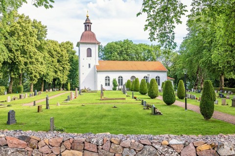Church with tombstones in the Swedish countryside with lush green trees a summer day, Kättilstorp,
