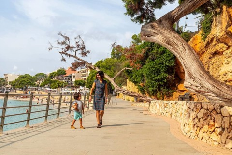 Mother and son enjoying a leisurely stroll along the picturesque seaside promenade in porto cristo,