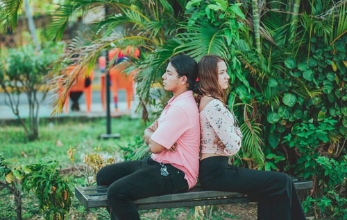 Upset young couple sitting back to back on a bench. Unhappy couple arguing on a public bench.
