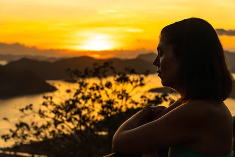 Silhouette of a tourist enjoying a beautiful golden sunset over coron island from mount tapyas