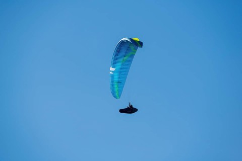A paraglider soars through a clear blue sky that promises adventure and freedom, Schwangau near