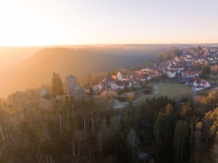 View of a village with a ruin in a hilly forest landscape at sunset, Zavelstein, district of Calw,