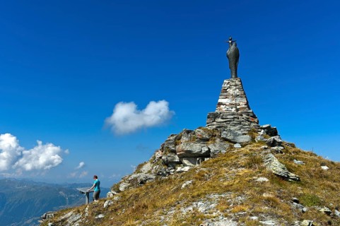 On the summit of Mont Noble, figure of the Virgin Mary with child and hiker at the panorama panel,