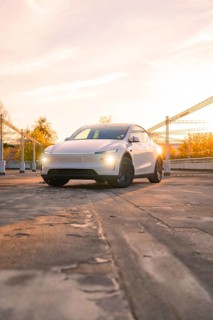 A white car in a city car park in the orange evening light, Tesla new Model Y Juniper, Nagold,