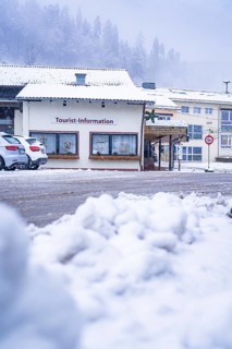 Tourist information centre with cars in the snow, situated under snow-covered roofs, Enzklösterle,