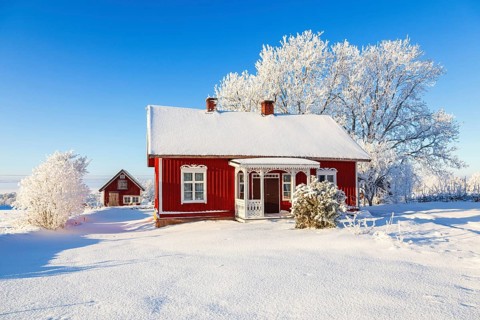 Idyllic old wooden red cottage a beautiful winter day with frosty trees and snow in the swedish