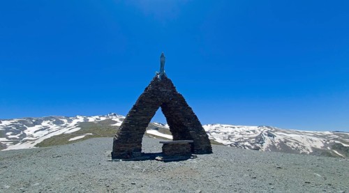 Chapel in a mountainous, snow-covered landscape under a clear blue sky, Virgen de las Nieves,