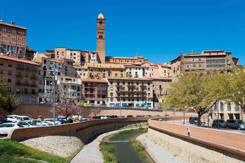 Cityscape with closely spaced houses and a river in the centre, dominated by a tower, church,