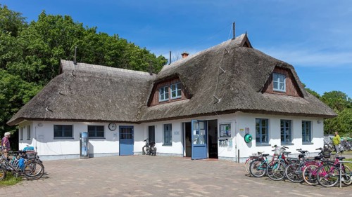 White, traditional thatched roof house with bicycles in front of it under a blue sky, Rügen,