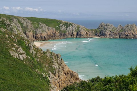 Felsen und Strand an einer Küste mit klarem Wasser und blauen Himmel, Porthcurno, St Levan,