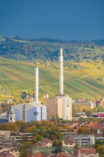Industrial building with tall chimneys against an urban backdrop and clear sky, Stuttgart, Germany
