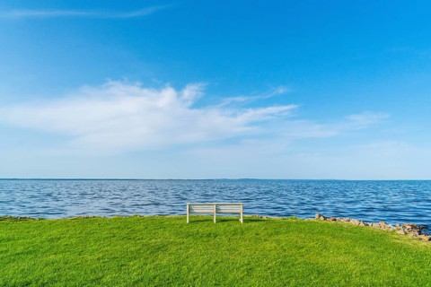 Isolated, white, empty bench in a meadow on the shore of the Szczecin Lagoon in the village of