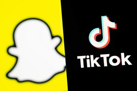 Tiktok logo is seen on a smartphone and Snapchat in the background