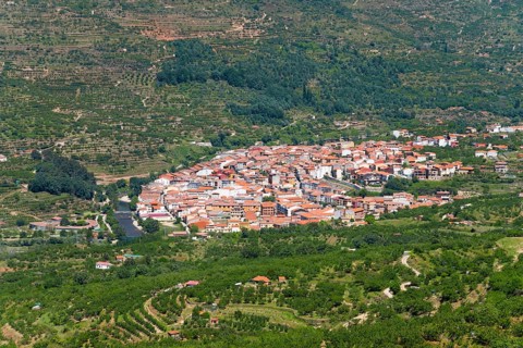 A village with white and red houses nestled in a green, hilly landscape, Cabezuela del Valle, Valle